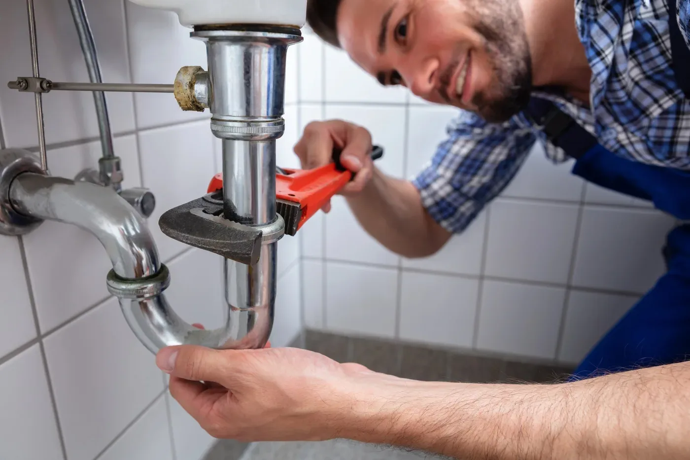 Plombier dégorgeant un siphon lors d'un débouchage à Sartrouville (78500)